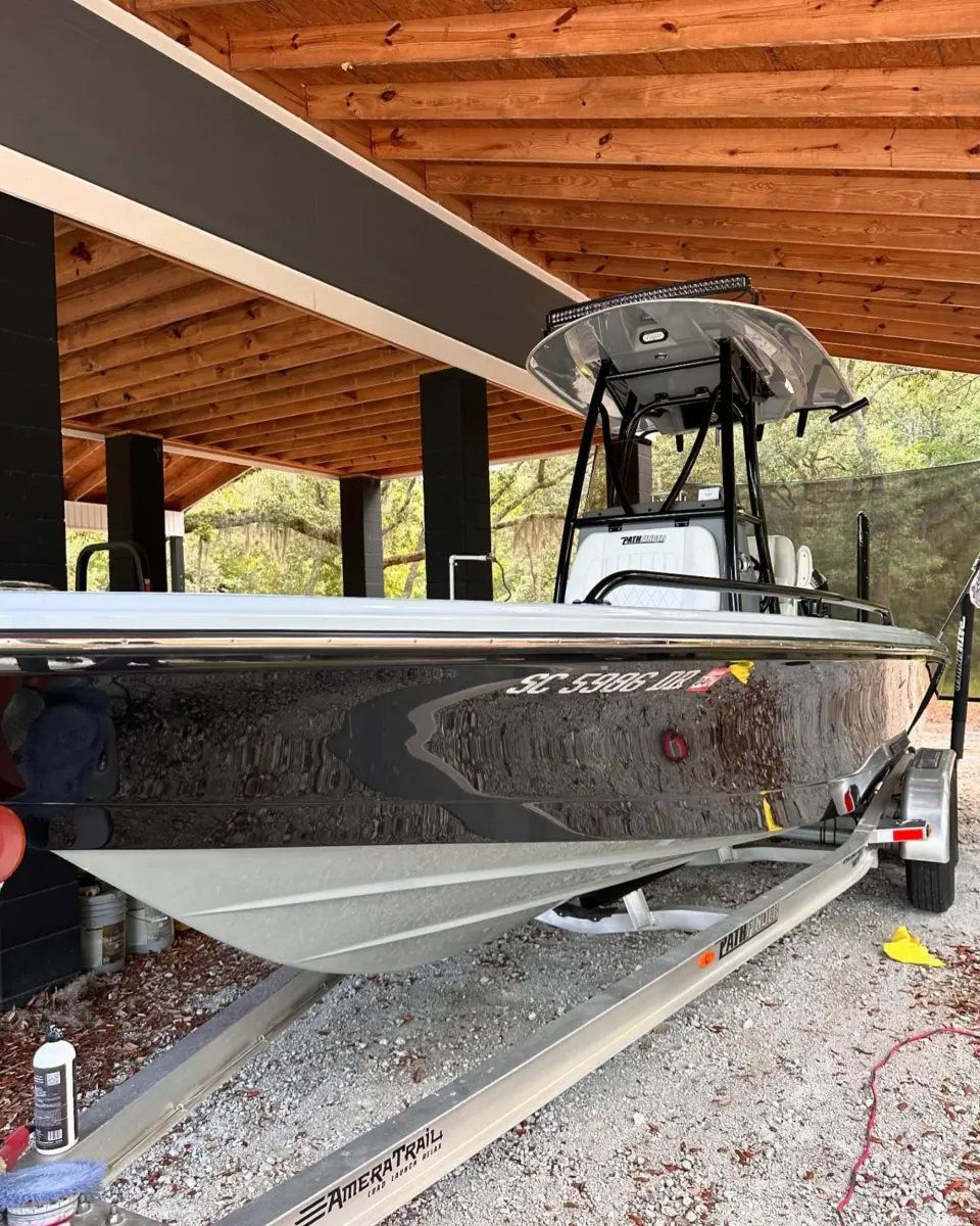 Dark-hulled center console on its trailer under a wooden roof
