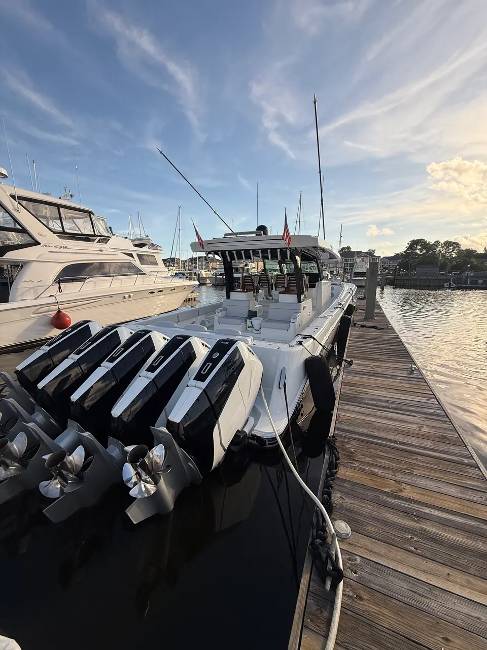 Center console with a row of outboards tied up at the dock in evening light